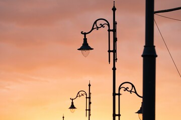 Low angle shot of old street lamps under sunset sky