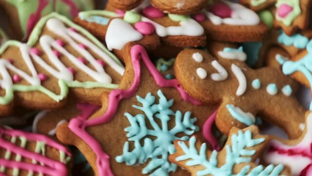 Gingerbreads decorated with frosting icing cream topping of different colours create holiday spirit waiting for Christmas. Decorated sweets put on plate
