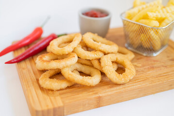 fast food breaded onion rings fried with sauce on a wooden board