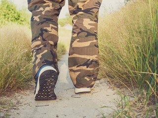 close-up of the legs of a man dressed in sneakers walking along a path in the forest. The concept of hiking, walking and a sporty lifestyle. rear view