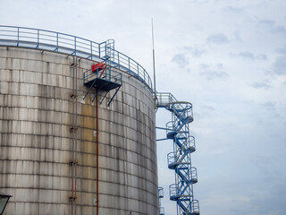 Large fuel tanks. Tanks and ladders of the tank farm. The gloomy atmosphere of an industrial area.