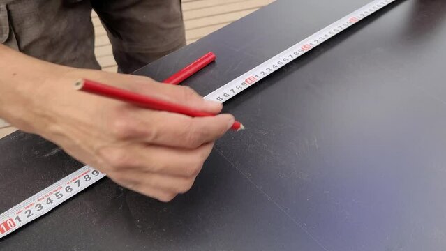 Carpenter measuring mdf boards with a tape measure and marking with a pencil. Constructing furniture