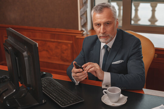 Male Hotelier Works At A Computer And Using Phone While Sitting In His Office In Hotel