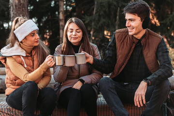 Three friends drinking tea from the metal, steel cups outdoors