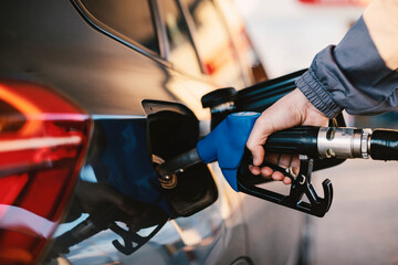 The hand of a gas station worker fills up the car tank. The expense of petroleum.