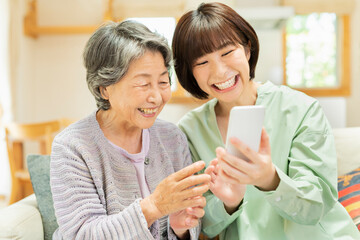 孫にスマートフォンの使い方を教わるシニア女性