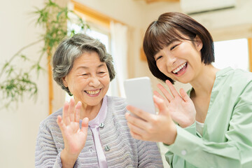 孫にスマートフォンの使い方を教わるシニア女性