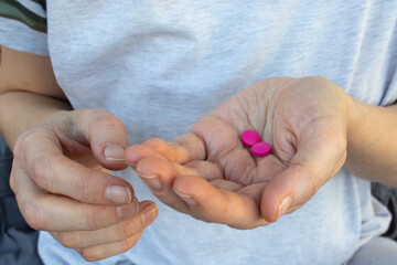 Person hand with pills. Woman holding two pink pills in hand. Healthcare, medicine concept. Patient take medicament, supplements, antibiotics, painkillers or antidepressants. Close up.