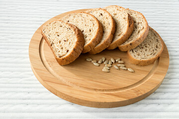 Sliced wheat hearth bread with sunflower seeds on the kitchen board.