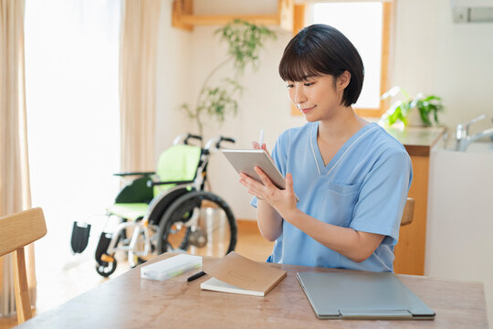 タブレットで日誌を書く女性医療従事者