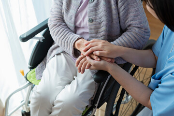 Fototapeta na wymiar 女性医療従事者と車椅子に乗ったシニア女性 手元