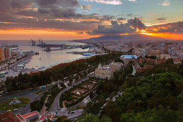 View of the Malaga city, Spain. Aerial view of City Hall and port with illuminated buildings at night with sunset sky