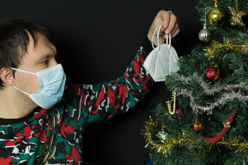A man with Covid-19 protection mask putting other masc on the christmas tree