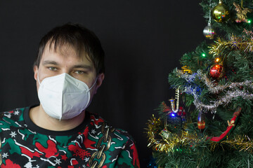A man with Covid-19 protection mask near the christmas tree