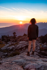Fototapeta premium Adventurous Woman Hiker on top of Canadian Mountain Landscape. Sunny Sunset Sky. Top of Mt Seymour near Vancouver, British Columbia, Canada. Adventure Travel Concept
