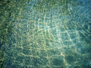 Defocus blurred transparent blue colored clear calm water surface texture with splash, bubble. Shining blue water ripple background. Surface of water in swimming pool. Blue bubble water shining.