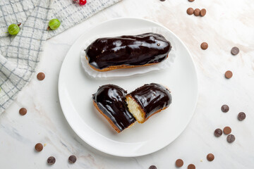 chocolate Eclair on a white plate on marble table top view