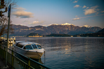 Boat next to shore and amazing landscape with lake como and snow-capped mountains (italian Alps or South Alps)