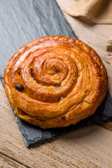 Snail with raisins on dark stone plate on wooden table vertical