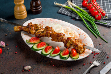 skewers of chicken wings with red onion on dark stone table