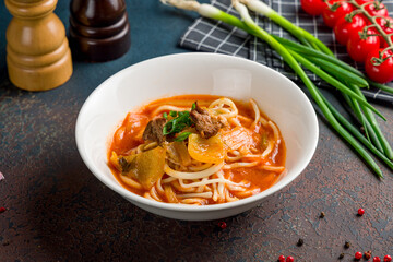 Lagman asian soup with noodles and beef on dark stone table