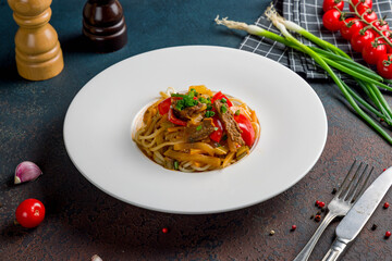 Uighur lagman Uzbek cuisine on white plate on dark table