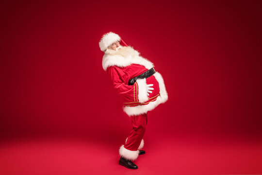 Real Santa Claus posing on red studio background. A lot of copy space. Xmas sale concept.