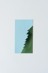 green foil shape (half tree) on blue paper with texture