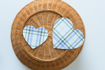 two blue plaid paper hearts on the bottom side of an upside down wicker basket