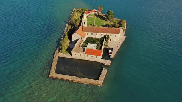 Aerial around view of the island of Notre Dame de la Misericorde, monastery in the Bay of Kotor, Montenegro. Ostrvo Gospa od Milosrda, 4k