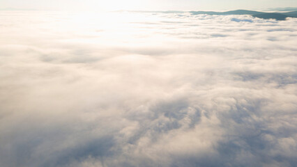 Fototapeta na wymiar Early Sunrise and Horizon over the clouds cover mountains ridge, aerial view