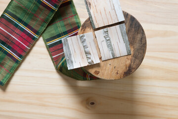 spool of holiday fabric ribbon in green and red plaid with cut pieces of birch bark