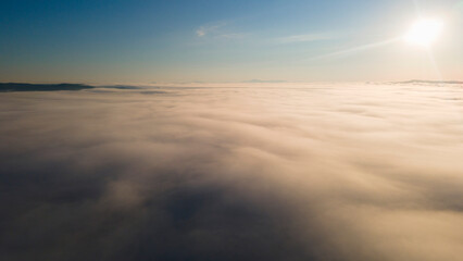 Fototapeta na wymiar Sun, Sunrays, Sunrise and Horizon over a clouds cover mountains ridge and pipe plant, aerial view