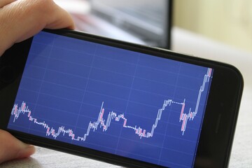 Person investing trading on the stock cryptocurrency market on a smartphone