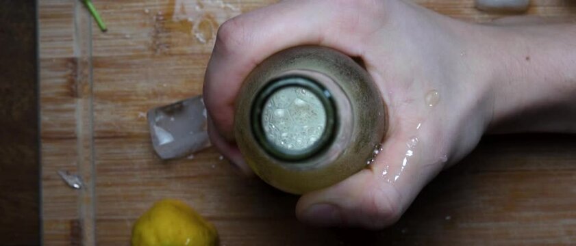 Beer bottle getting slammed onto a table with ice and lemons