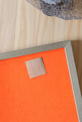 cut birch bark square on orange felt set within a framed panel on wood