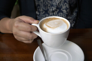 Close up of a woman's hand holding a cup of coffee
