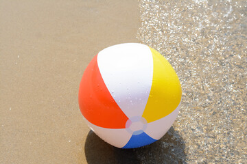 Obraz premium Colorful beach ball on wet sand at seaside