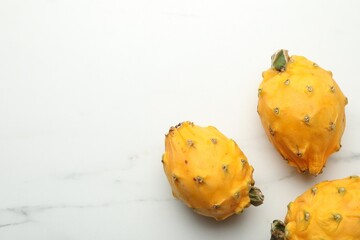 Delicious yellow pitahaya fruits on white marble table, flat lay. Space for text