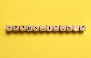 Word Appendicitis made of wooden cubes with letters on yellow background, top view