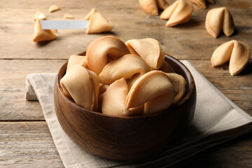 Tasty fortune cookies with prediction on wooden table, closeup