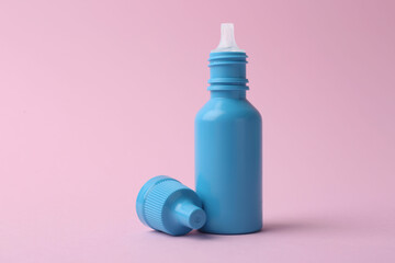 Bottle of medical drops on pink background