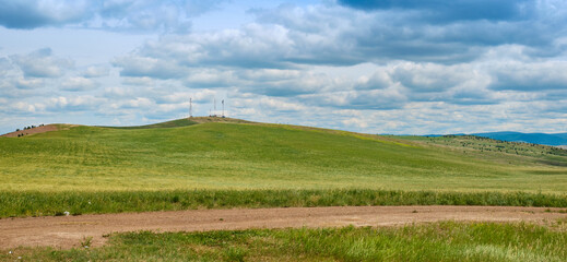 Fototapeta na wymiar Bald Mountain in the Buryat Republic of Russia. Green hills against a blue sky with clouds.
