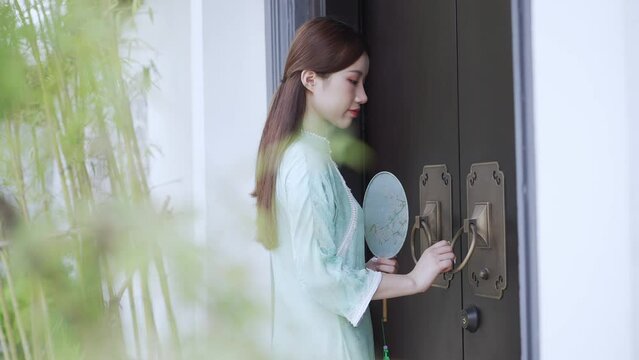 young beautiful chinese woman in qipao knocking at the door