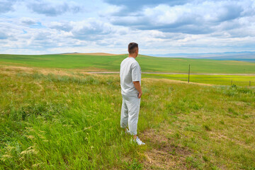 A man in light-colored clothes stands on the cliff of a hill and looks towards the Buryat Selenga River near the city of Ulan-Ude © rdv27