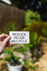 sustainability and circular economy, reduce reuse recycle sign in front of backyard bokeh