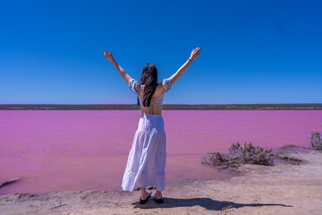 Fototapeta na wymiar A teenager girl reached arms out facing pink lake in Perth, West Australia