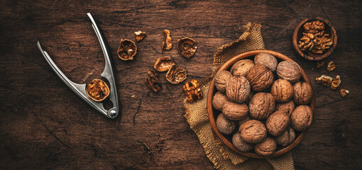 Fresh raw walnuts, autumn food background, nuts harvest and nutcracker. Old rustic wooden background, top view, banner