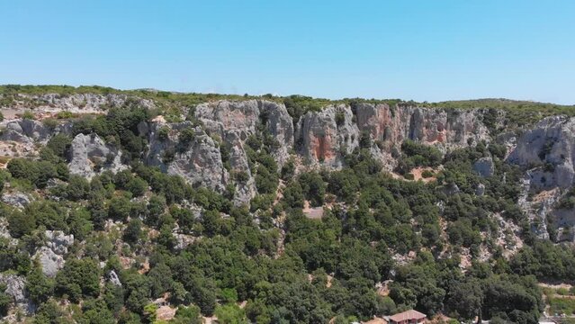 Flug über Gesteinsmassiv Steinhang Kliff mit Schiefer und Kalkstein auf Sardinien in Italien mit Drohne aus der Vogelperspektive in 4k