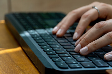 young mexican latina woman, typing on a wireless keyboard on her computer